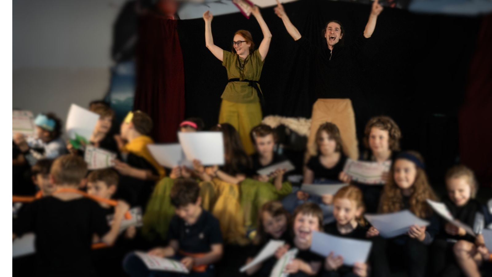 Marzia Laini e Federico Lotteri applaudono insieme ai bambini di una scuola primaria al termine di uno spettacolo teatrale nella scuola, con i diplomi di partecipazione in mano
